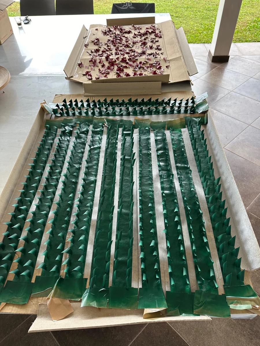Triangoli d’alluminio verniciati di verde fissati in file su strisce, con altri triangoli bordeaux ad asciugare