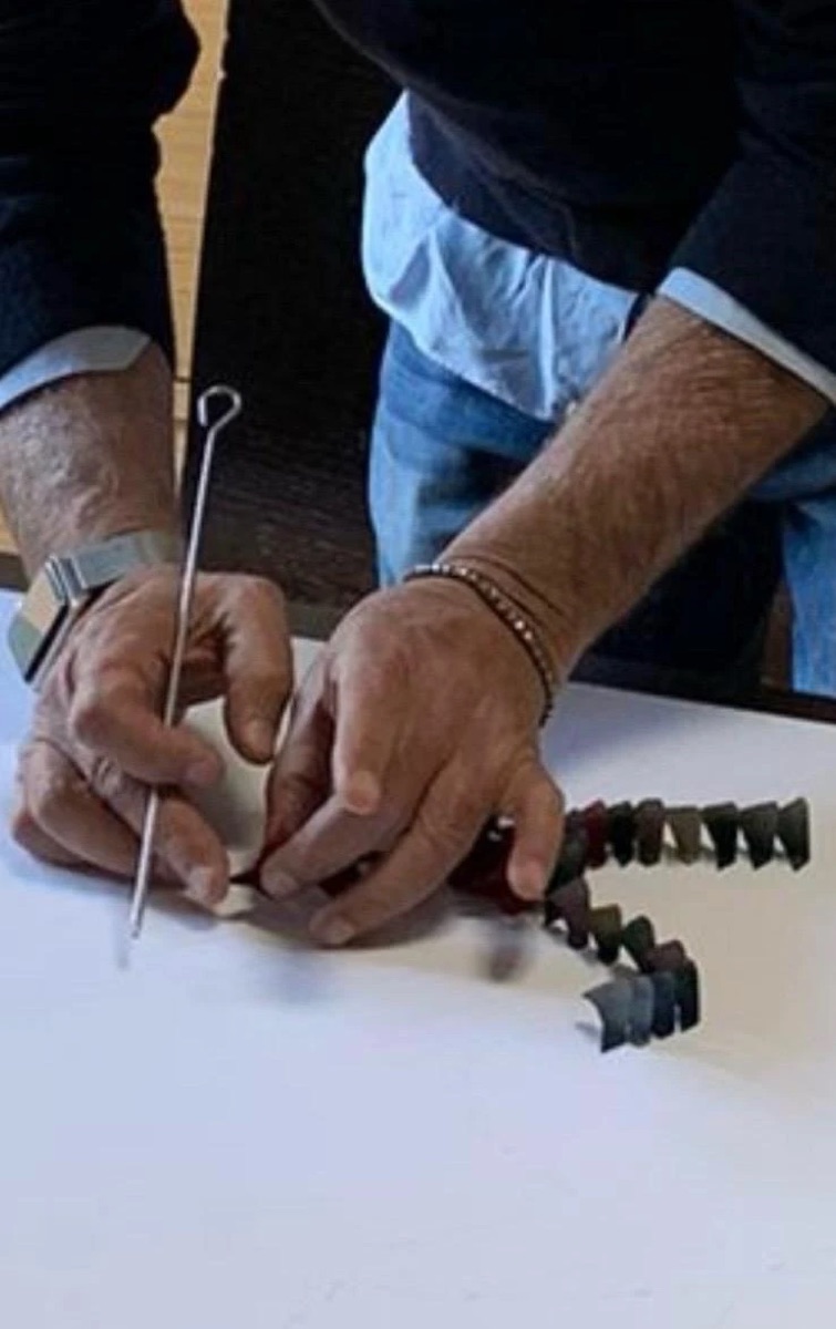 Le mani di Giuseppe posizionano i triangoli uno accanto all’altro aiutandosi con un ago
