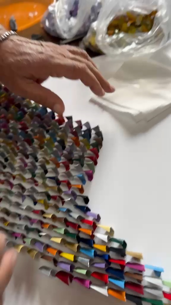 La mano di Giuseppe accanto a centinaia di triangoli colorati già assemblati in file